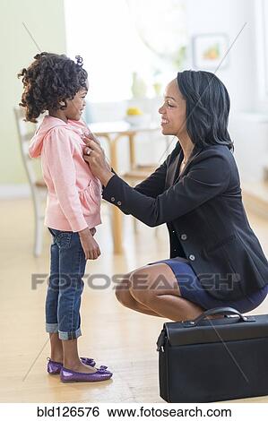 Stock Photograph - Black mother dressing daughter. Fotosearch