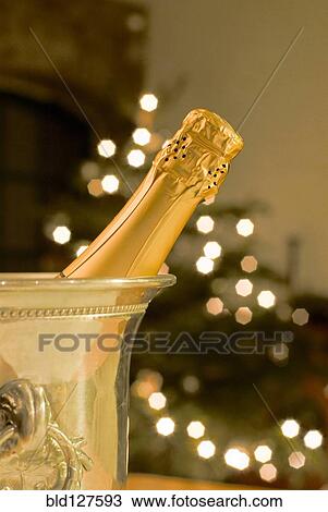 Bottle of champagne in cooler with Christmas tree in background View Large Photo Image Stock Image - Bottle of champagne in cooler with Christmas tree in background. Fotosearch