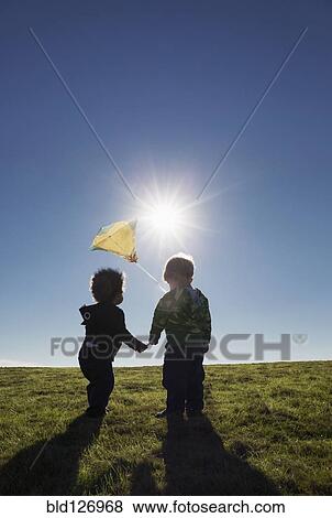 Stock Photo - Boys watching kite flying against blue sky. Fotosearch