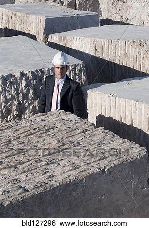 Stock Photograph - bsuinessman standing in labyrinth of marble blocks. Fotosearch