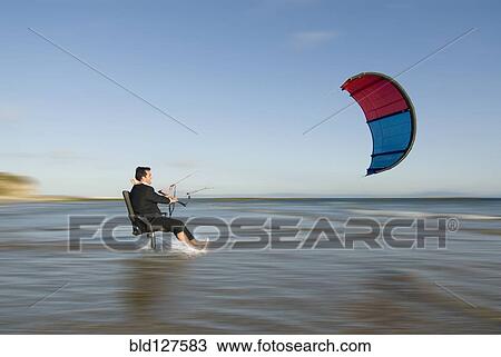 Businessman on chair pulled by surfing kite in sea View Large Photo Image Stock Image - Businessman on chair pulled by surfing kite in sea. Fotosearch