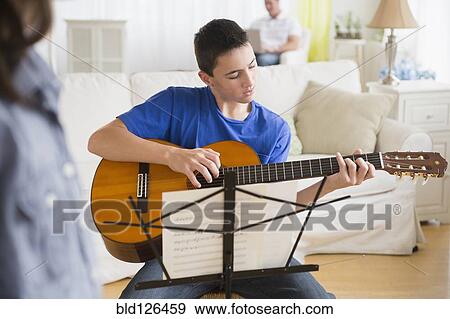 Caucasian boy practicing guitar in living room View Large Photo Image Stock Photo - Caucasian boy practicing guitar in living room. Fotosearch