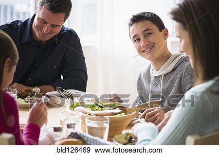 Stock Photo - Caucasian family eating at table. Fotosearch