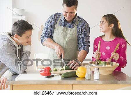 Stock Photo - Caucasian father and children preparing salad in kitchen. Fotosearch