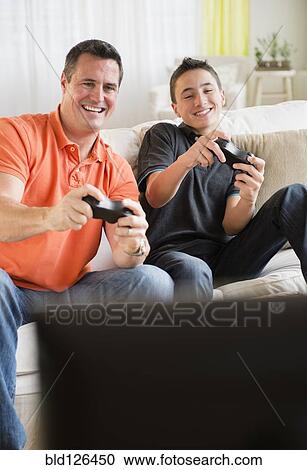 Caucasian father and son playing video games in living room View Large Photo Image Stock Image - Caucasian father and son playing video games in living room. Fotosearch
