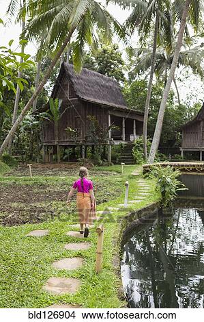 Picture - Caucasian girl walking on path in garden, Ubud, Bali, Indonesia. Fotosearch