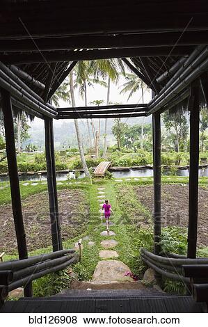 Stock Photo - Caucasian girl walking on path in garden, Ubud, Bali, Indonesia. Fotosearch