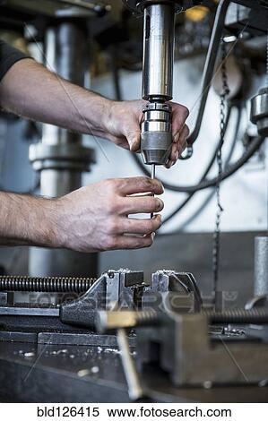 Stock Photography - Caucasian man operating drill machinery in metal shop. Fotosearch