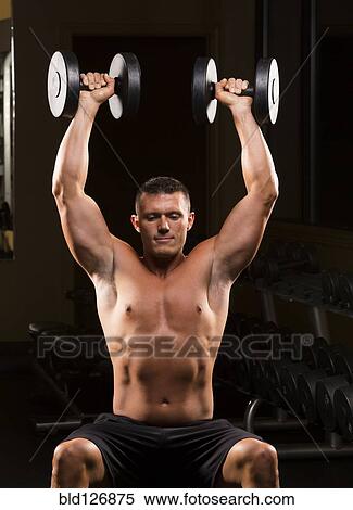 Stock Photography - Caucasian man with bare chest lifting dumbbells overhead. Fotosearch