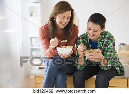 Stock Image - Caucasian mother and son eating cereal together. Fotosearch