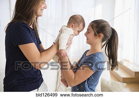 Caucasian mother handing baby girl to daughter View Large Photo Image Stock Photo - Caucasian mother handing baby girl to daughter. Fotosearch