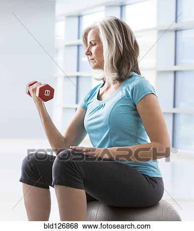 Caucasian woman doing biceps curls with dumbbell View Large Photo Image Stock Photo - Caucasian woman doing biceps curls with dumbbell. Fotosearch
