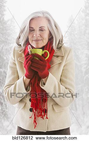 Stock Image - Caucasian woman drinking hot chocolate outdoors. Fotosearch