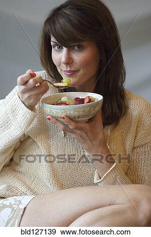 Caucasian woman eating bowl of fruit View Large Photo Image Stock Photo - Caucasian woman eating bowl of fruit. Fotosearch