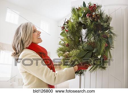Caucasian woman hanging Christmas wreath on door View Large Photo Image Stock Image - Caucasian woman hanging Christmas wreath on door. Fotosearch