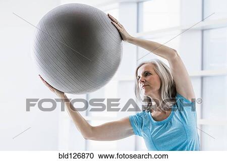 Stock Image - Caucasian woman leaning with fitness ball. Fotosearch
