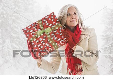 Caucasian woman shaking Christmas gift View Large Photo Image Stock Photograph - Caucasian woman shaking Christmas gift. Fotosearch