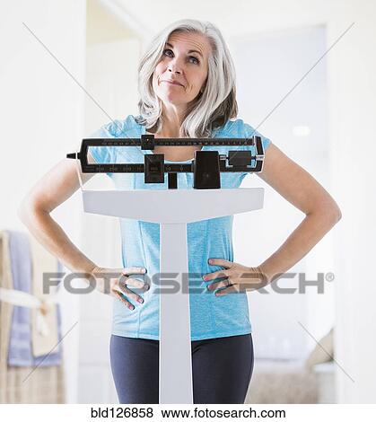 Caucasian woman shrugging on weight scale View Large Photo Image Stock Photo - Caucasian woman shrugging on weight scale. Fotosearch