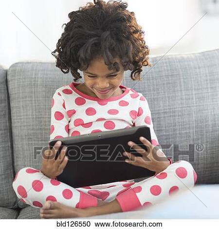 Close up of African American girl in pajamas using digital tablet View Large Photo Image Stock Image - Close up of African American girl in pajamas using digital tablet. Fotosearch