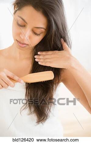 Stock Image - Close up of Asian woman brushing hair. Fotosearch