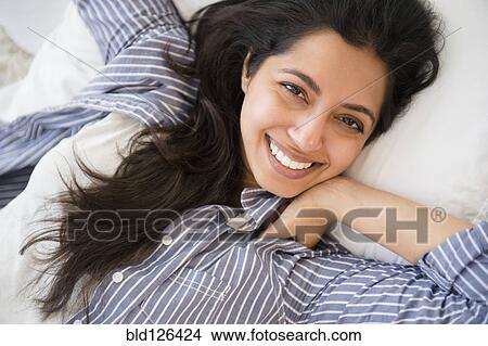 Close up portrait of smiling Asian woman laying in bed View Large Photo Image Picture - Close up portrait of smiling Asian woman laying in bed. Fotosearch