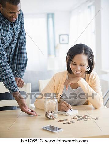 Stock Image - Couple counting savings at table. Fotosearch
