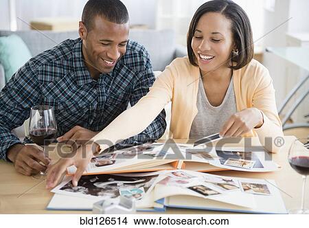Couple drinking red wine and looking at photographs View Large Photo Image Picture - Couple drinking red wine and looking at photographs. Fotosearch