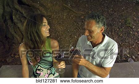 Stock Image - Couple drinking red wine in outdoors setting. Fotosearch