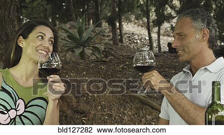 Couple drinking red wine in outdoors setting View Large Photo Image Stock Image - Couple drinking red wine in outdoors setting. Fotosearch