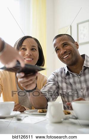 Stock Image - Couple receiving bill from waitress in restaurant. Fotosearch