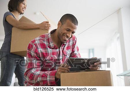 Couple with digital tablet and moving boxes View Large Photo Image Stock Photography - Couple with digital tablet and moving boxes. Fotosearch