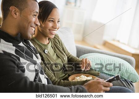 Couple with popcorn watching TV in living room View Large Photo Image Stock Image - Couple with popcorn watching TV in living room. Fotosearch