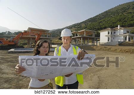 Engineer and architect looking at plan on construction site View Large Photo Image Stock Image - Engineer and architect looking at plan on construction site. Fotosearch