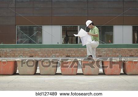 Engineer studying plan on construction site smiling profile View Large Photo Image Stock Photo - Engineer studying plan on construction site smiling profile. Fotosearch