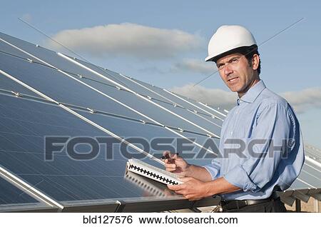 Stock Photograph - engineer with plans and solar panels. Fotosearch