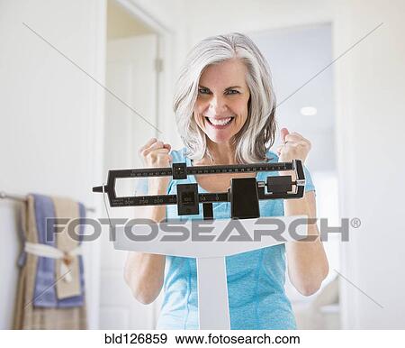 Excited Caucasian woman cheering on weight scale View Large Photo Image Stock Photo - Excited Caucasian woman cheering on weight scale. Fotosearch