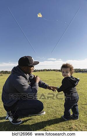 Father and son flying kite in park View Large Photo Image Stock Photograph - Father and son flying kite in park. Fotosearch