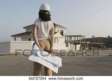 Female architect with plan looking at house in new development View Large Photo Image Picture - Female architect with plan looking at house in new development. Fotosearch