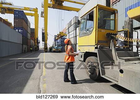 Female worker with clipboard in cargo container terminal View Large Photo Image Stock Photo - Female worker with clipboard in cargo container terminal. Fotosearch