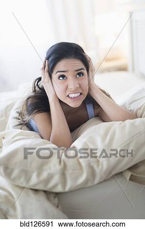 Frustrated Hispanic woman covering ears in bed View Large Photo Image Stock Image - Frustrated Hispanic woman covering ears in bed. Fotosearch