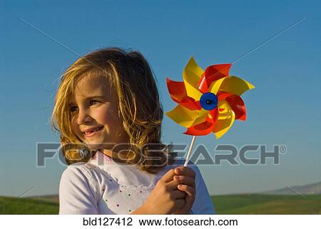 Girl holding pinwheel in field View Large Photo Image Stock Image - Girl holding pinwheel in field. Fotosearch