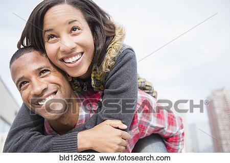 Stock Image - Happy couple piggybacking. Fotosearch