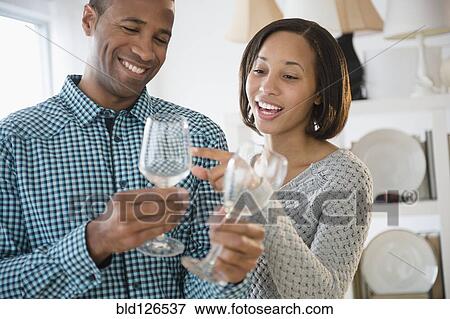 Stock Photo - Happy couple shopping for wine glasses. Fotosearch
