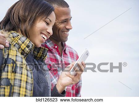 Happy couple using cell phone outdoors View Large Photo Image Stock Image - Happy couple using cell phone outdoors. Fotosearch