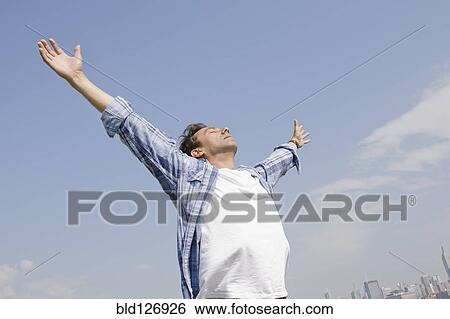 Hispanic man standing with arms outstretched against blue sky View Large Photo Image Stock Photograph - Hispanic man standing with arms outstretched against blue sky. Fotosearch