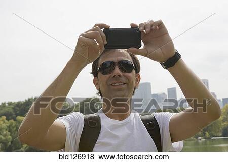 Stock Photo - Hispanic man using camera phone. Fotosearch