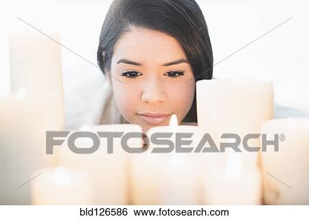 Stock Photograph - Hispanic woman looking down at lit candles. Fotosearch
