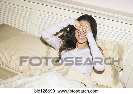 Hispanic woman rubbing eyes in bed View Large Photo Image Stock Photo - Hispanic woman rubbing eyes in bed. Fotosearch