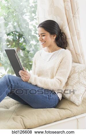 Hispanic woman using digital tablet at window seat View Large Photo Image Stock Photo - Hispanic woman using digital tablet at window seat. Fotosearch