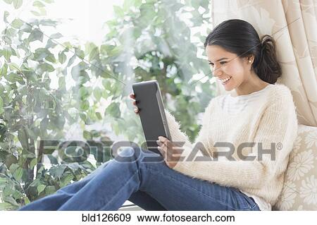 Hispanic woman using digital tablet at window seat View Large Photo Image Stock Photo - Hispanic woman using digital tablet at window seat. Fotosearch